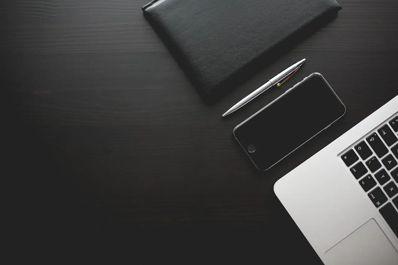 Schreibtisch mit Smartphone und Laptop — typisches COPE-Setup im Mittelstand mit kontrolliertem Mobile Device Management