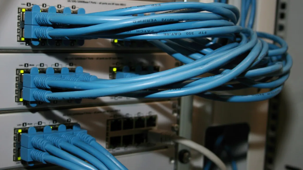 Blaue Netzwerk-Geräte im Server-Rack mit Port-Anschlüssen — HPE Aruba Switches mit PoE+ für Mittelstand-Netze