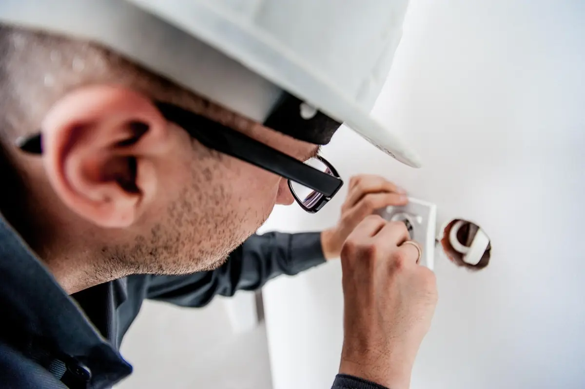 Elektriker an einer Steckdose — Stromversorgung als Basis für jedes Netzteil
